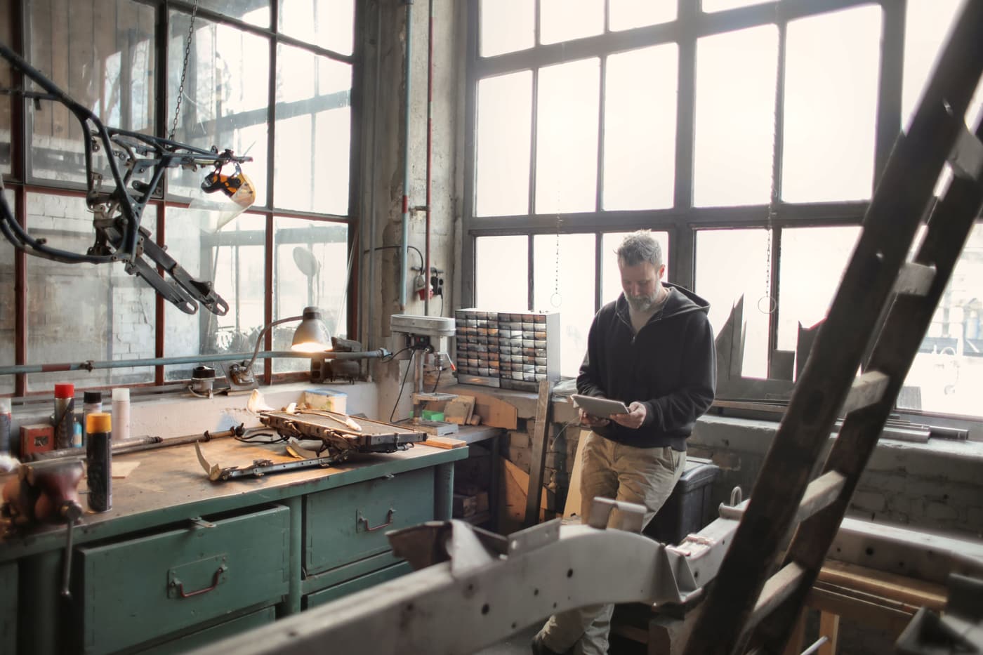 Artisan dans son atelier de mécanique, consultant sa demande de financement sur tablette