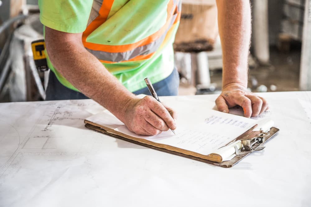 Chef de chantier notant une commande sur son plan de travail