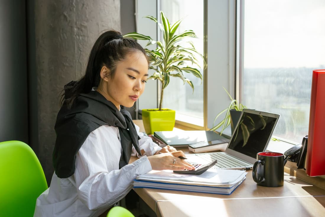 Experte-comptable à son bureau, calculatrice et dossiers clients