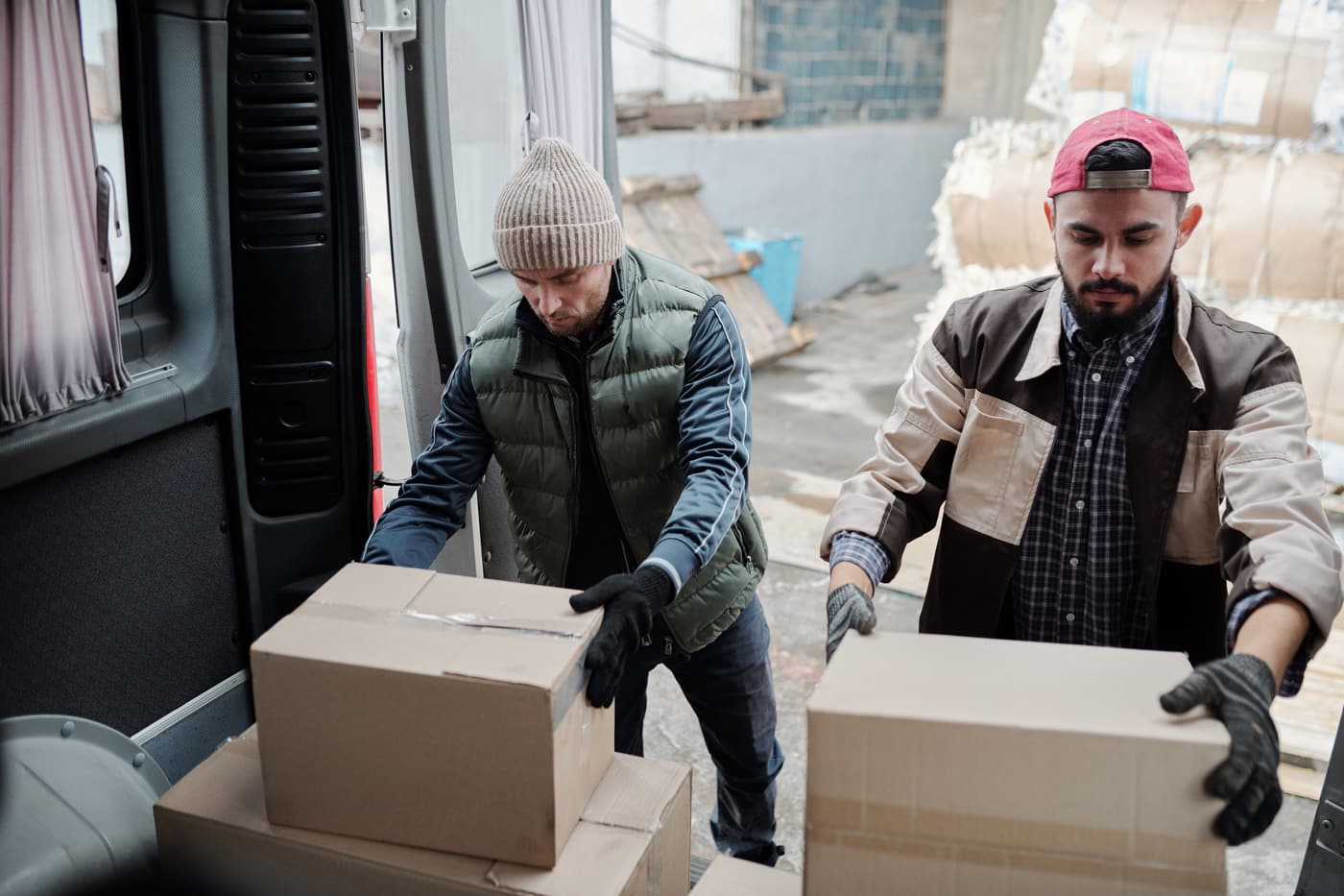 Deux livreurs déchargent des colis d’un utilitaire professionnel